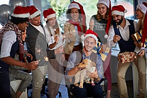 Workers celebrating Christmas together at work. business people in santa hat with Christmas present