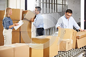 Workers Checking Goods On Belt In Distribution Warehouse