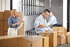 Workers Checking Goods On Belt In Distribution Warehouse