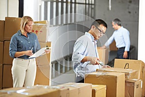 Workers Checking Goods On Belt In Distribution Warehouse