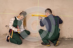 Workers checking walls with laser level tool photo