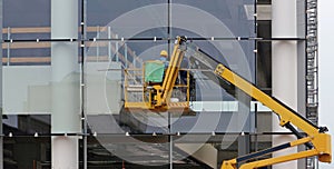 Workers on a cherry picker. They are finishing the glass facade of a building under renovation