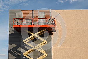 Workers on a cherry picker refurbish the facade of a building by applying aluminum panels cladding