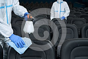Workers cleaning chairs with disinfectants in cinema. photo