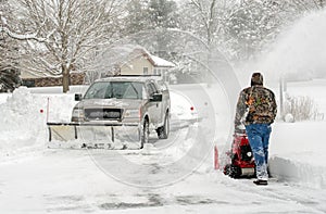 Workers clearing snow with blower and snow plow