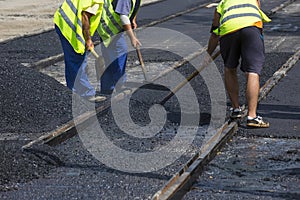 Workers construct asphalt road and railroad lines