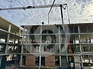 Workers at a construction site against the backdrop of the construction of a high-rise building. Builders work against the