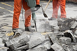 Workers at construction site demolishing asphalt