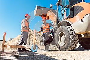 Workers on construction site discussing the use of tools