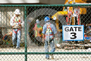 Workers in construction site, focus on chain link fence.