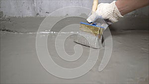 The process of applying mortar - waterproofing to a concrete floor. The concept of waterproofing the floor with a brush.