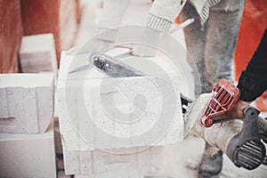 Workers cutting autoclaved aerated concrete block with chainsaw closeup. Builders cutting white blocks for masonry installation.