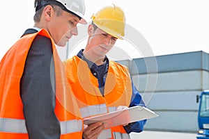 Workers discussing over clipboard in shipping yard