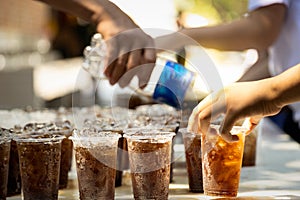 Workers are distribute free beverages or black water to people,.soft drink is poured into a glass of plastic,beverages for
