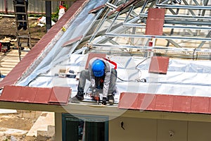 Workers are drilling roof tiles with a drill.