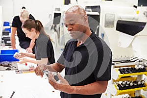 Workers In Engineering Factory Checking Component Quality