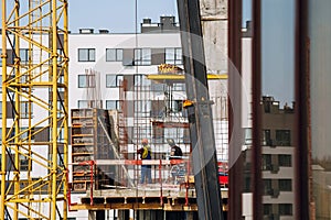 Workers engineers working at construction site and cranes on background of new building skyscrapers. Industrial landscape with bu