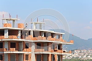 Workers erect balconies from brick in new building photo