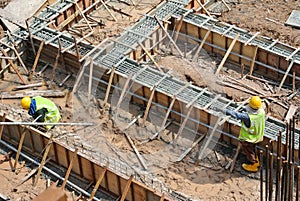Workers fabricating ground beam reinforcement bar