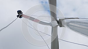 Workers fix wind-driven generator blade under cloudy sky