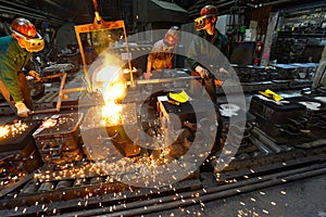 Workers in a foundry casting a metal workpiece - safety at work and teamwork