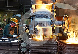 Workers in a foundry casting a metal workpiece - safety at work and teamwork