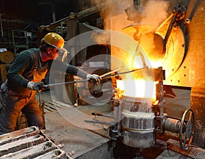 Workers in a foundry casting a metal workpiece - safety at work and teamwork