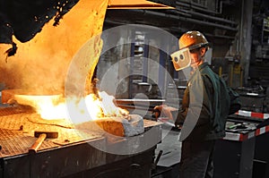 Workers in a foundry casting a metal workpiece - safety at work and teamwork