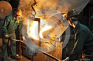 Workers in a foundry casting a metal workpiece - safety at work and teamwork