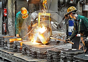 Workers in a foundry casting a metal workpiece - safety at work and teamwork