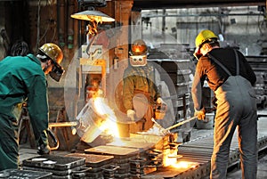 Workers in a foundry casting a metal workpiece - safety at work and teamwork