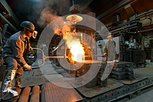 Workers in a foundry casting a metal workpiece - safety at work and teamwork photo