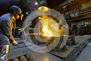 Workers in a foundry casting a metal workpiece - safety at work and teamwork