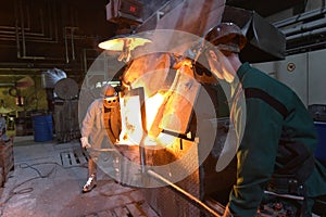 Workers in a foundry casting a metal workpiece - safety at work and teamwork