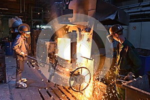 Workers in a foundry casting a metal workpiece - safety at work and teamwork