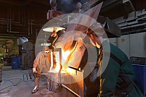 workers in a foundry casting a metal workpiece - safety at work and teamwork