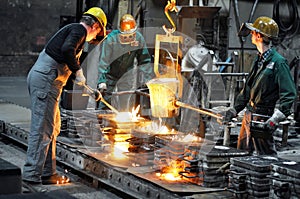 Workers in a foundry casting a metal workpiece - safety at work and teamwork photo