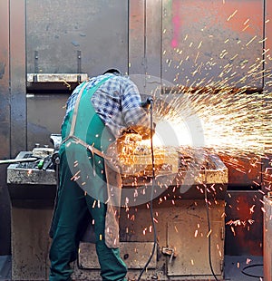 Workers in a foundry grind castings with a grinding machine - He