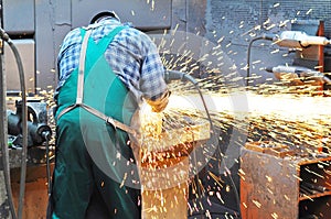 Workers in a foundry grind castings with a grinding machine - He