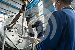 Workers handling equipment for lifting industrial boilers