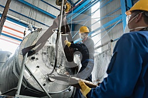 Workers handling equipment for lifting industrial boilers