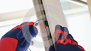 Workers hands adjusting locks of open pvc windows with special key