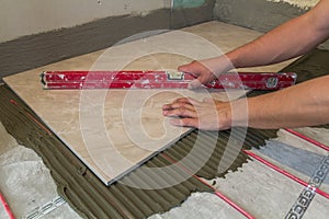 Workers hands with ceramic tiles and tools for tiler. Floor tile