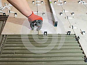 Workers hands with ceramic tiles and tools for tiler. Floor tiles installation. Ceramic tile floor adhesive, mortar