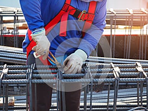 workers hands using steel wire and pincers to secure rebar