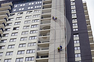 Workers hang on the building and doing electrical installations