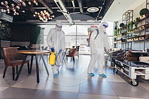Workers in hazmat suits disinfecting indoor of cafe or restaurant, pandemic health risk, coronavirus