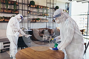 Workers in hazmat suits disinfecting indoor of cafe or restaurant, pandemic health risk, coronavirus