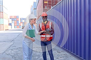 Workers with helmet at logistic shipping cargo containers yard. African engineer man using digital tablet to report results