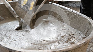 Workers help mix Concrete in a tray at Construction Site with hoes